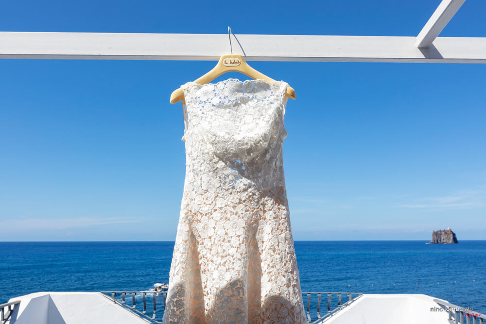 Image of the wedding dress with Strombolicchio in the background with a beautiful sea